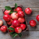 Red round apples sitting on a weathered grey wooden table