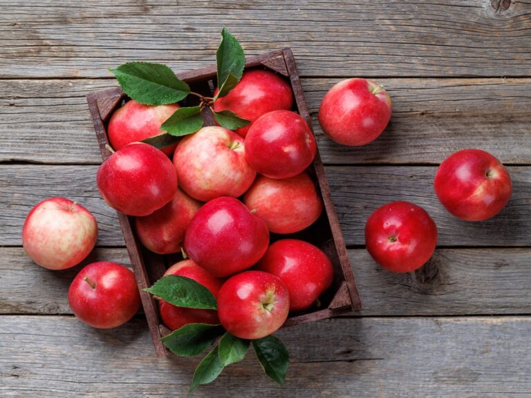 Red round apples sitting on a weathered grey wooden table